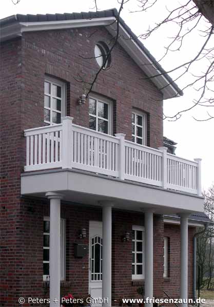 Hausbau Neubau - Der Balkon über dem Eingangsbereich wird mit einem weißem Holzgeländer aus ODUM-IROKO Hartholz gesichert.