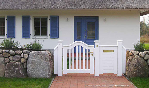 Wunderschönes Reetdachhaus mit einem typischem Friesenwall und einer weißen Gartentür mit Briefkasten.